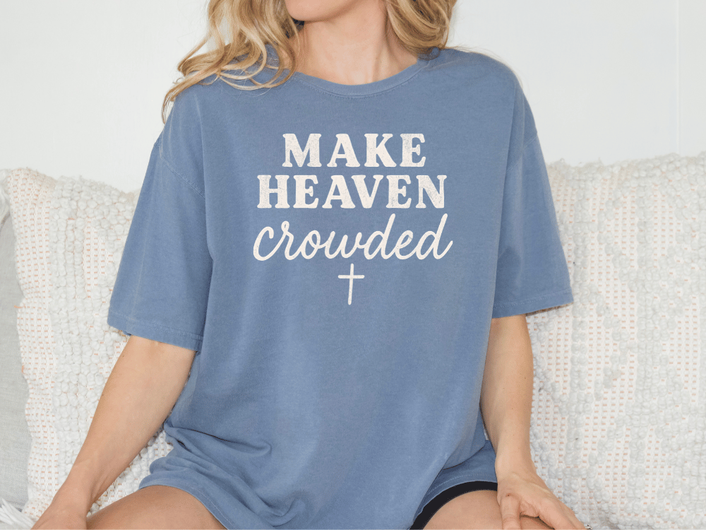 A woman wearing a blue t-shirt with the text "MAKE HEAVEN CROWDED" printed on it.