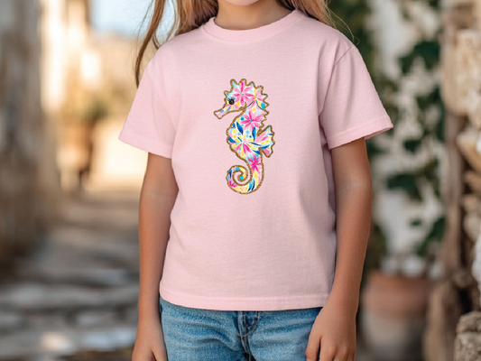 a little girl wearing a pink shirt with a seahorse on it