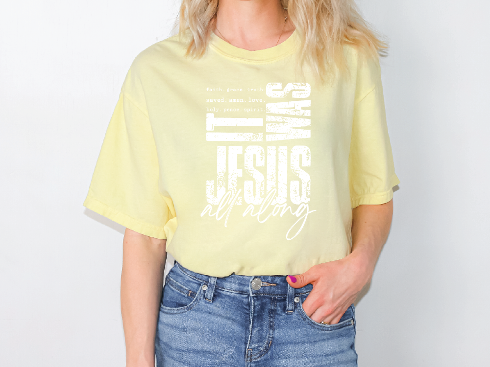 A woman wearing a yellow t-shirt with the text "It was all along" printed on it.