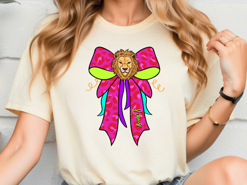 A woman wearing a white t-shirt with a colorful graphic design of a lion's head on a bow.