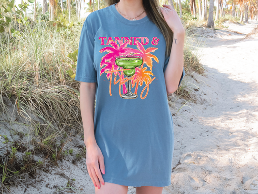a woman standing on a beach wearing a blue shirt dress