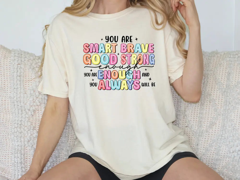 a woman sitting on a couch wearing a t - shirt that says, you are