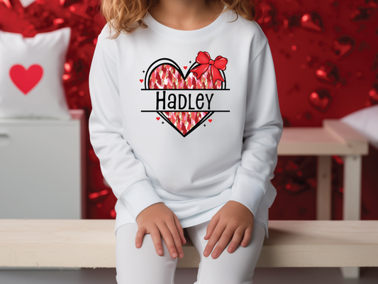 a little girl sitting on a bench wearing a sweatshirt