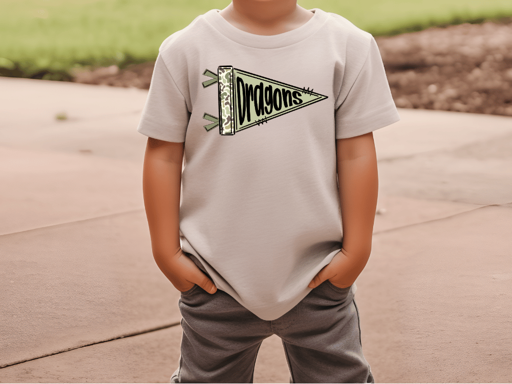 A child wearing a white t-shirt with a dragon design and gray pants standing on a concrete surface.