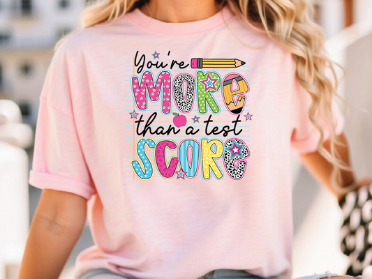 a woman wearing a pink shirt that says you're more than a test score