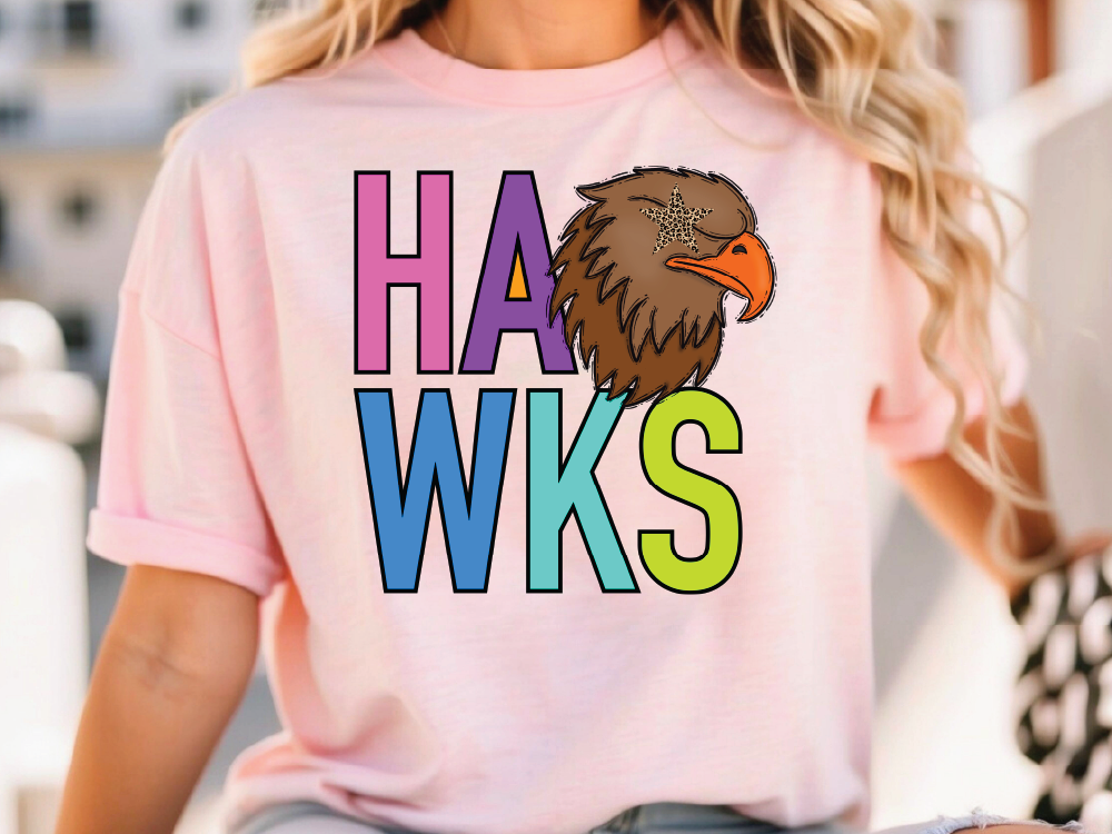A woman wearing a pink t-shirt with the text "HAWS" printed on it, along with an illustration of a hawk.
