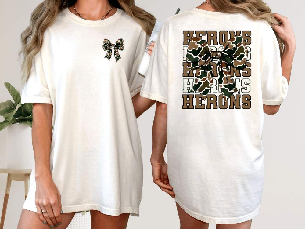 A woman wearing a white t-shirt with a camouflage print and the text "HERONS" printed on the back.