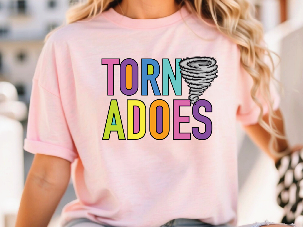 A woman wearing a pink t-shirt with the text "TORNADO ADOES" printed on it.