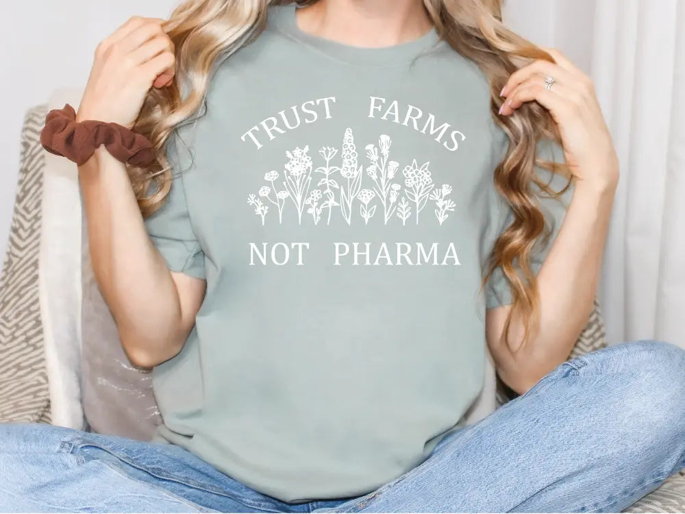 a woman sitting on a couch holding a t - shirt that says trust farms not