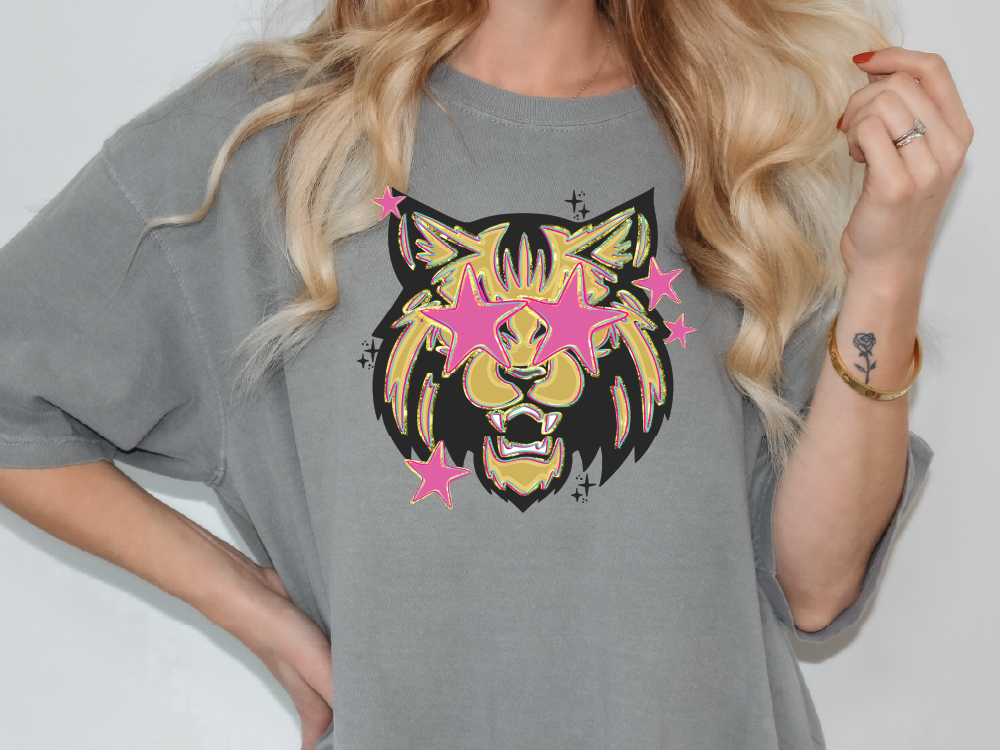 A woman wearing a gray t-shirt with a graphic design of a lion's face and stars on it.