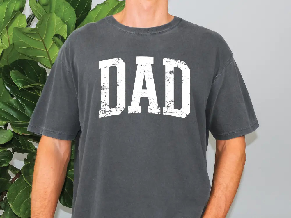 a man standing in front of a plant wearing a t - shirt that says dad