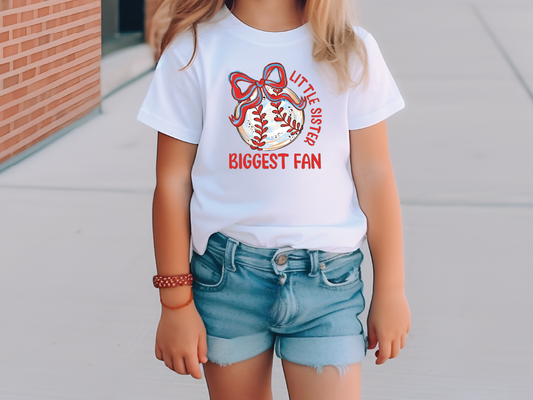 a little girl wearing a white shirt with a baseball on it