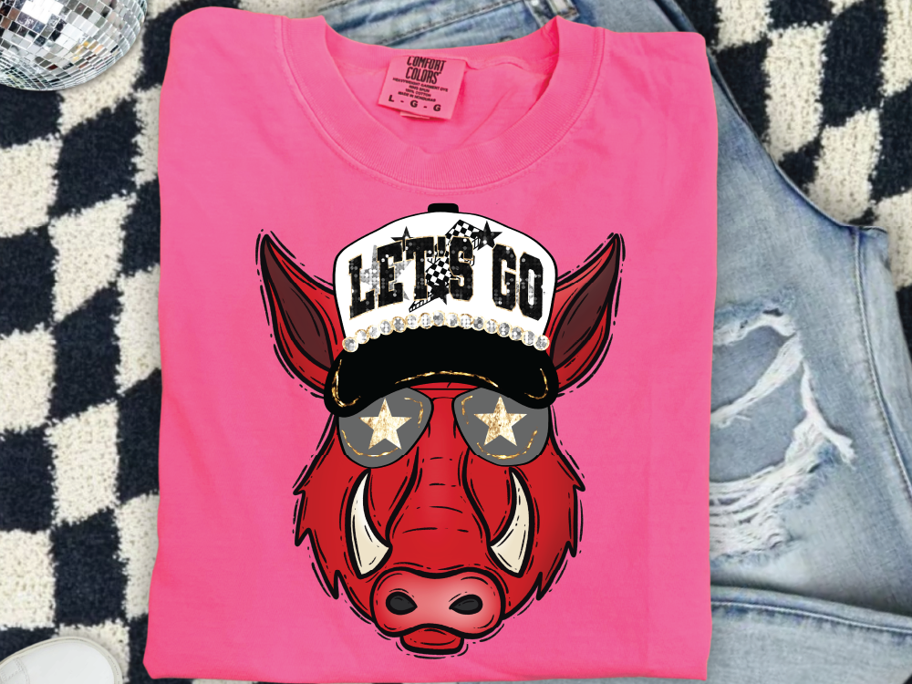 A pink t-shirt with a graphic of a red boar wearing sunglasses and a baseball cap, along with the text "LET'S GO".