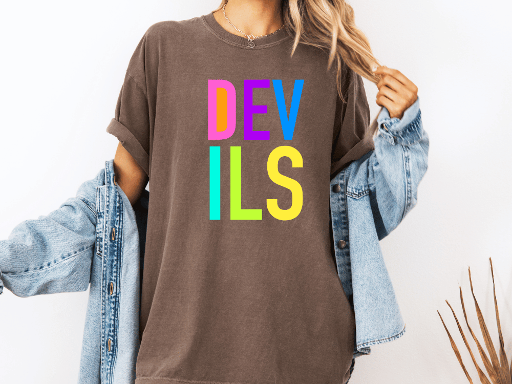 A person wearing a brown t-shirt with the word "DEVILS" printed on it, along with a denim jacket.