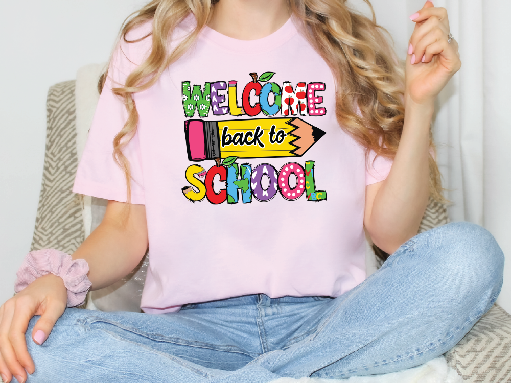 A woman wearing a pink t-shirt with a colorful graphic that says "Welcome back to school".