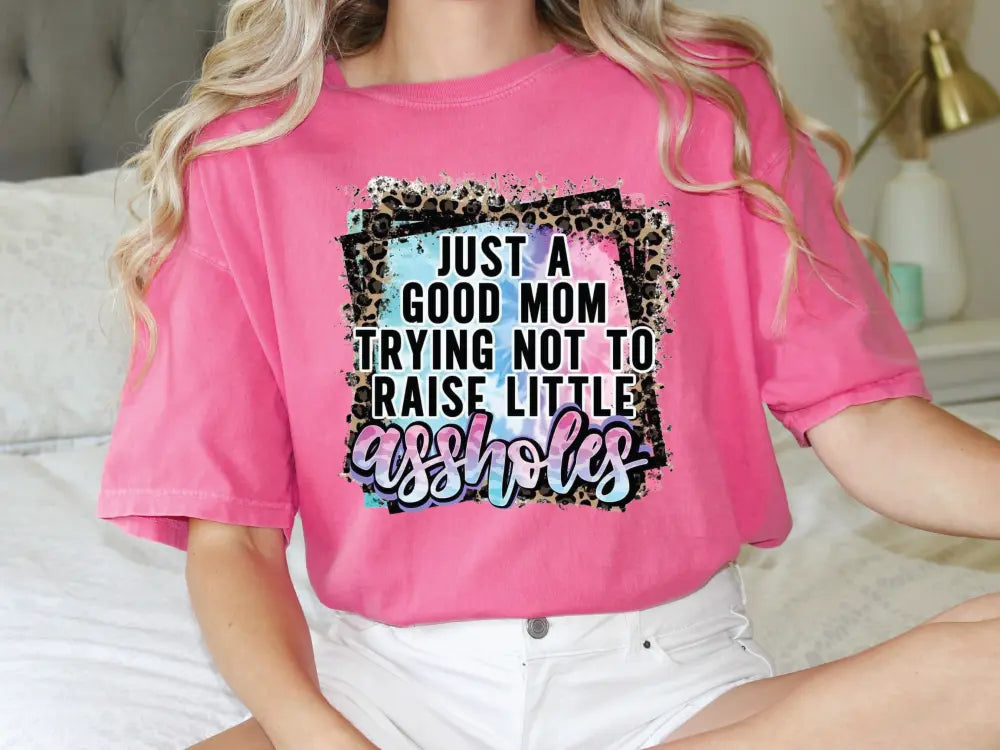 a woman sitting on a bed wearing a pink shirt