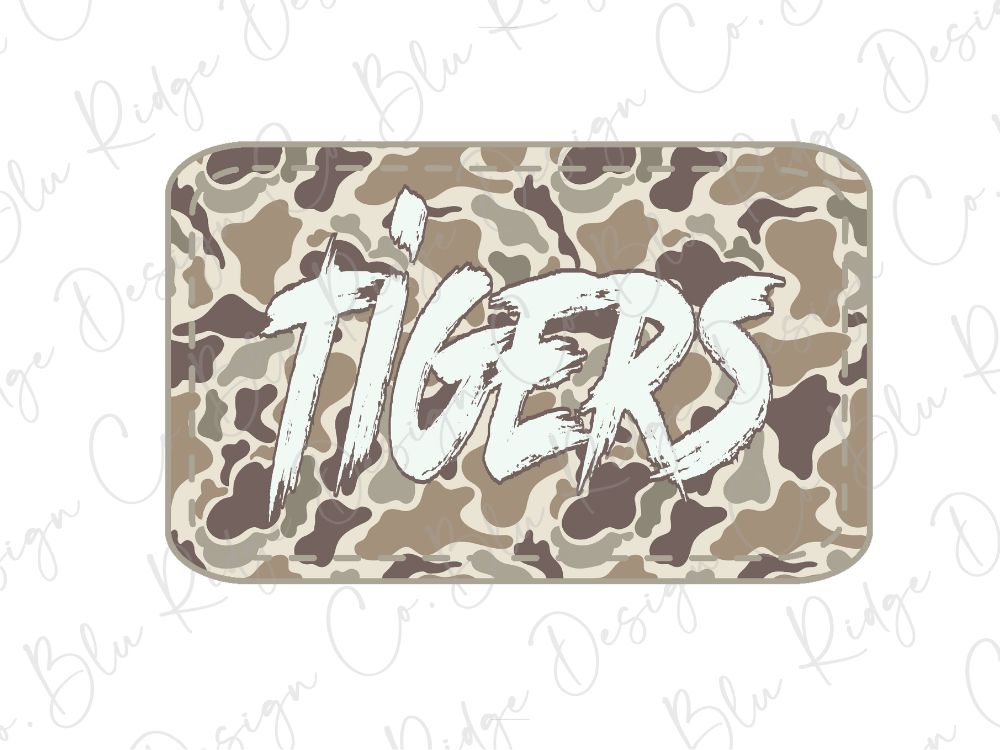A camouflage-patterned rectangular object with the word "TIGERS" written in bold, white brushstrokes on it.