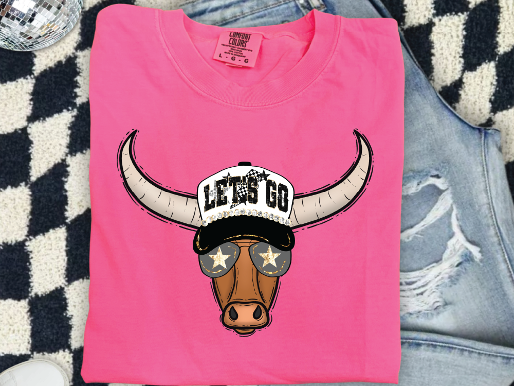 A pink t-shirt with a cartoon bull wearing sunglasses and a hat with the text "LET'S GO" printed on it.