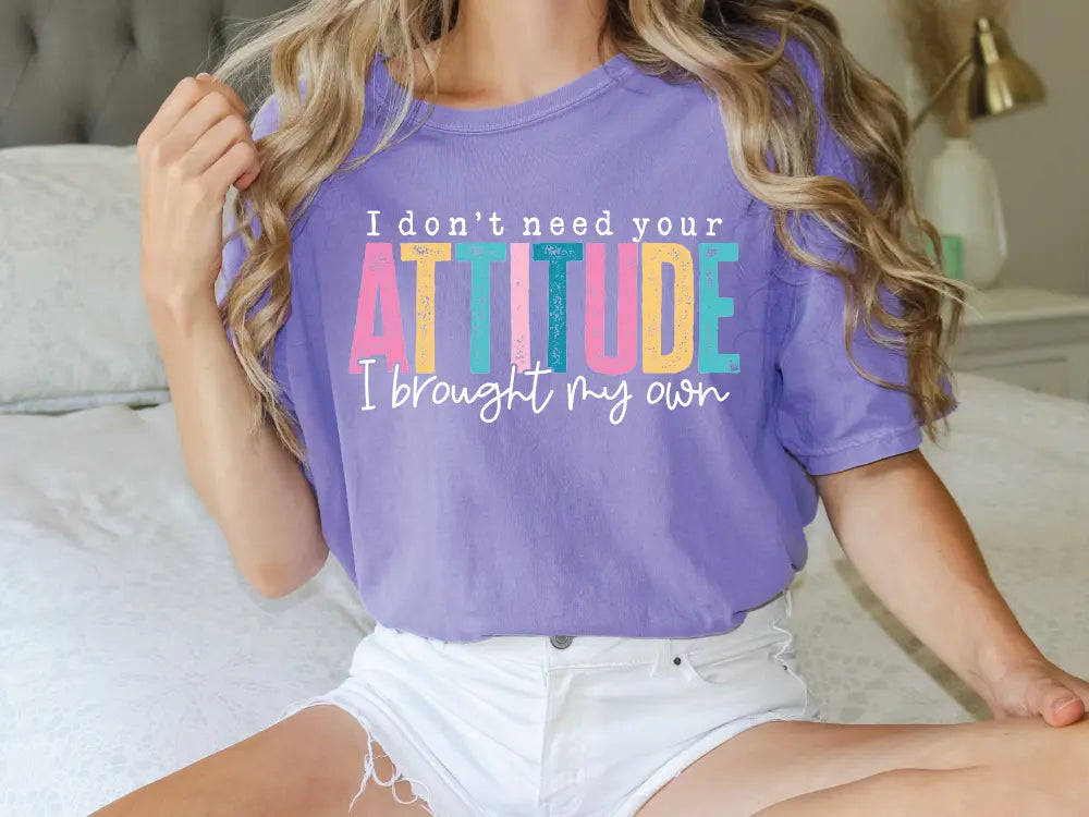 a woman sitting on a bed wearing a purple shirt