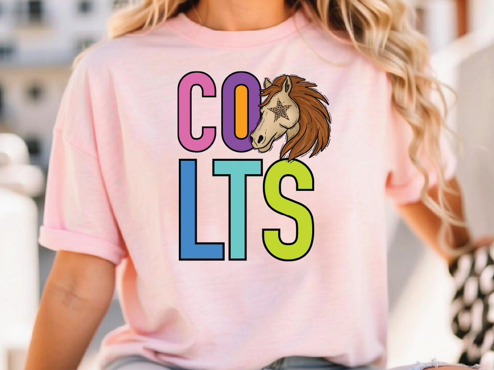 A woman wearing a pink t-shirt with the text "COLTS" printed on it.