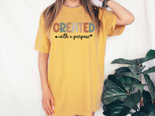 a woman wearing a yellow t - shirt with the words created with purpose printed on