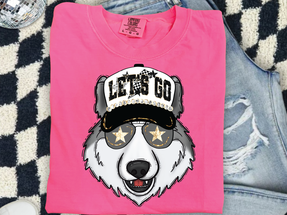 A pink t-shirt with a graphic of a wolf wearing sunglasses and a hat with the text "LET'S GO" printed on it.