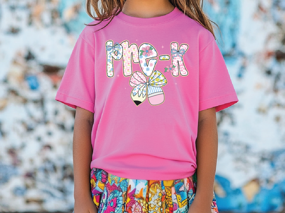 a little girl wearing a pink shirt and colorful shorts