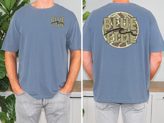 a man standing in front of a plant wearing a blue shirt