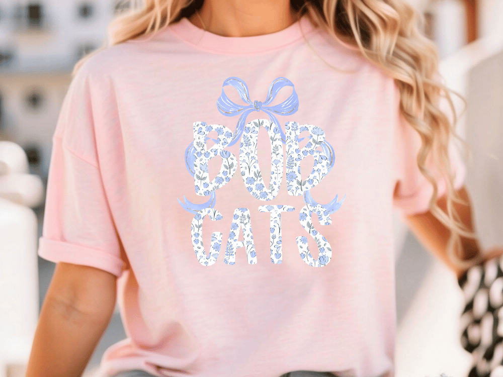 A woman wearing a pink t-shirt with the text "BOP CATS" printed on it.
