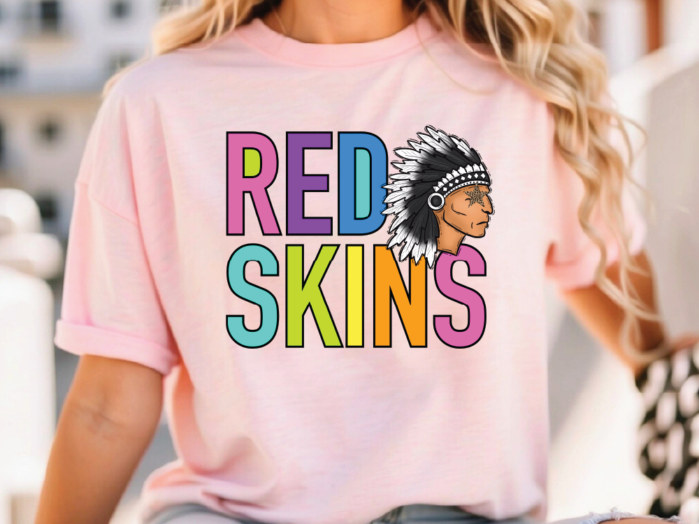 A woman wearing a pink t-shirt with the text "RED SKINS" printed on it.