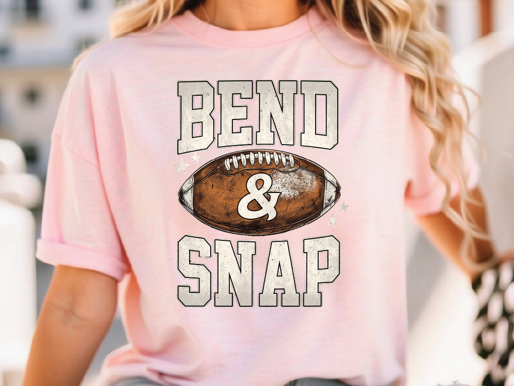 A woman wearing a pink t-shirt with the text "BEND & SNAP" printed on it.