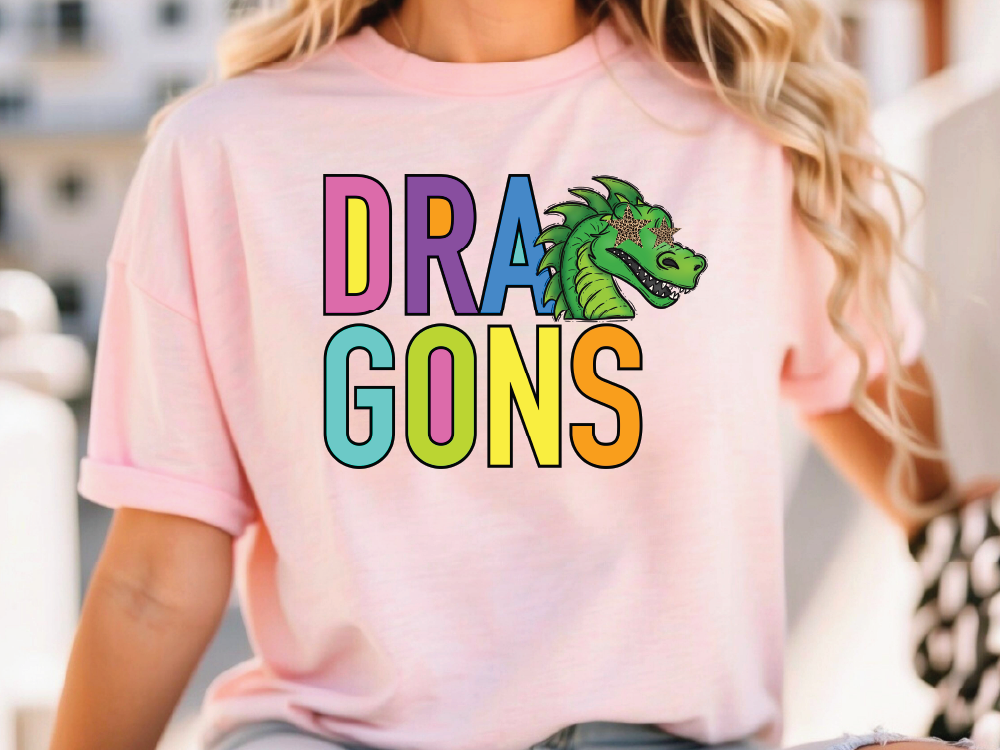 A person wearing a pink t-shirt with the text "DRA GONS" printed on it, along with a colorful dragon graphic.