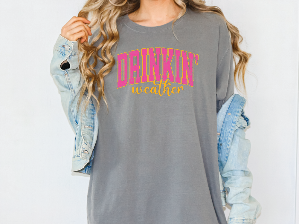 a woman wearing a gray shirt with pink and yellow lettering