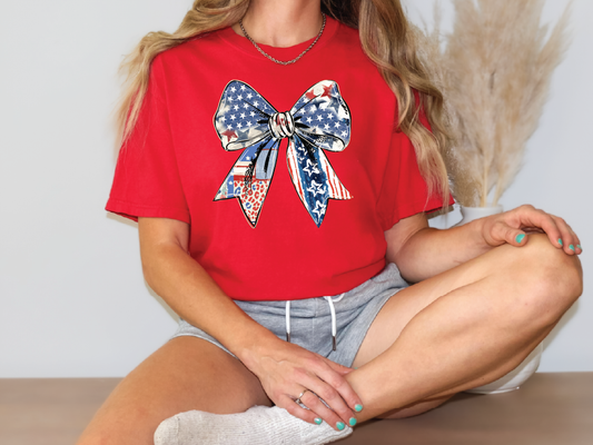 a woman sitting on a table wearing a red shirt with a bow on it