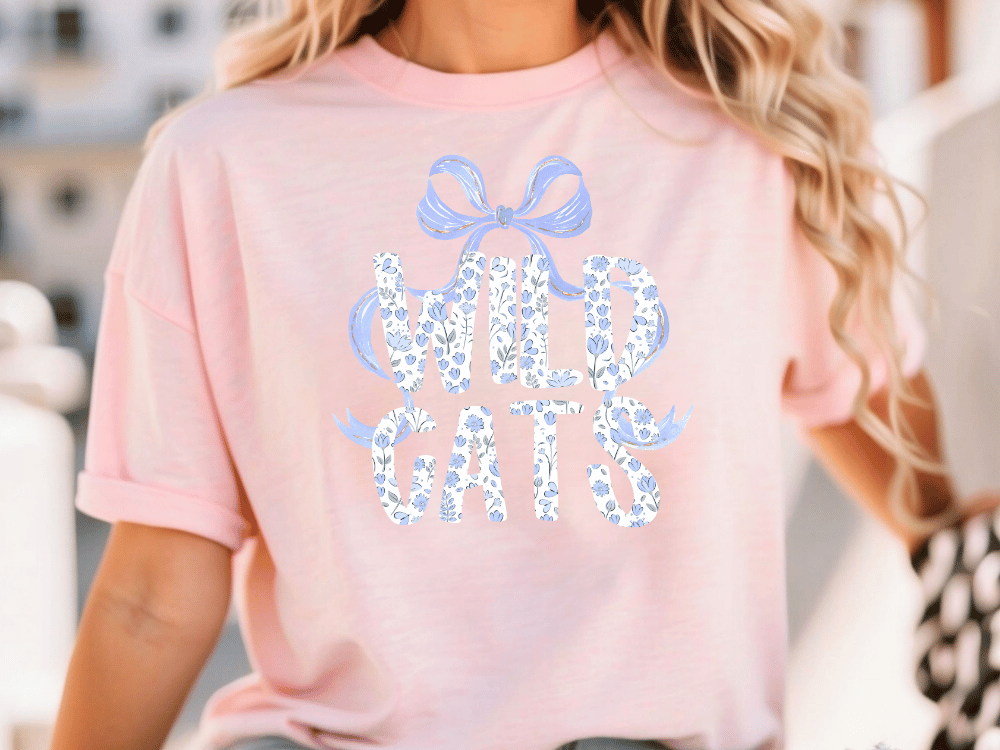 A woman wearing a pink t-shirt with the text "WILD GATS" printed on it.