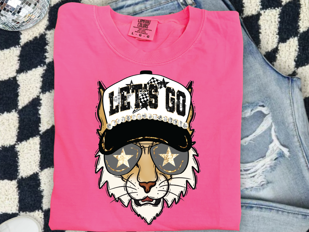 A pink t-shirt with a graphic design of a tiger wearing sunglasses and a hat with the text "LET'S GO" printed on it.