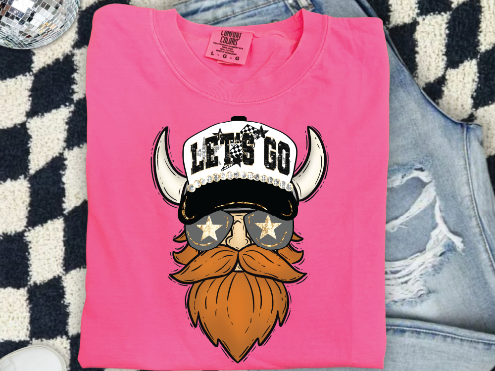 A pink t-shirt with a graphic design of a bearded Viking wearing sunglasses and a hat with the text "LET'S GO" printed on it.