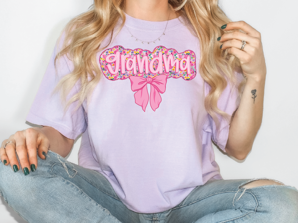 a woman sitting on the floor wearing a purple shirt with a pink bow