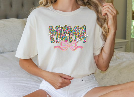 a woman sitting on a bed wearing a white shirt