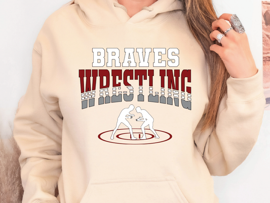 A person wearing a beige hoodie with the text "Braves Wrestling Inc." printed on it.