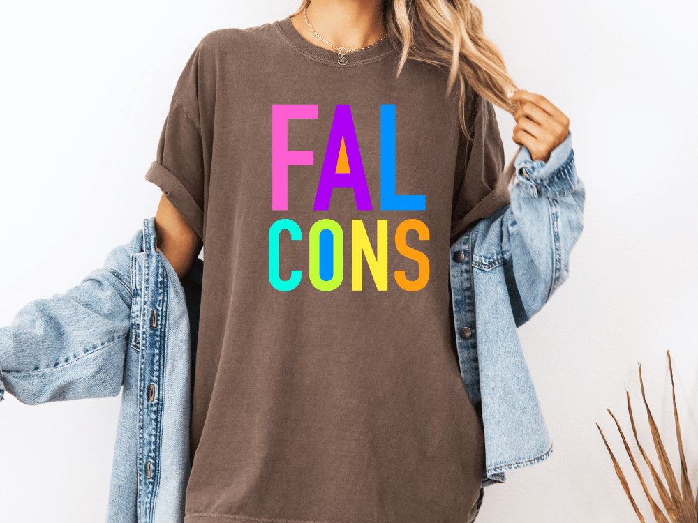 A person wearing a brown t-shirt with the text "FAL CONS" in colorful letters, along with a denim jacket, stands against a white background.