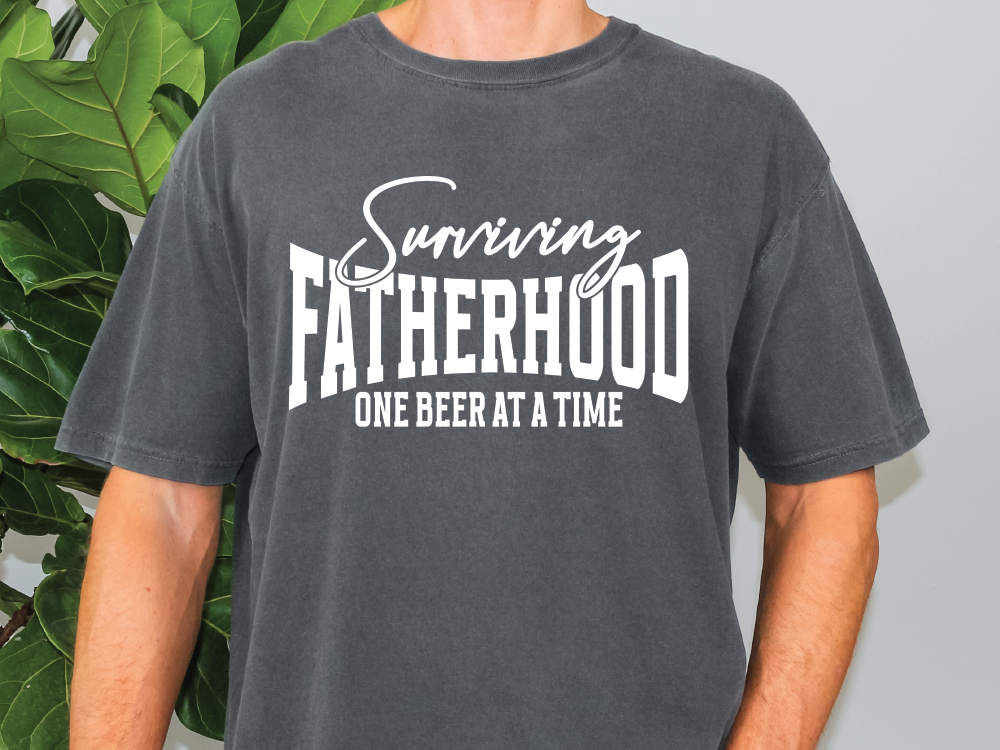 a man wearing a t - shirt that says,'surviving fatherhood one beer