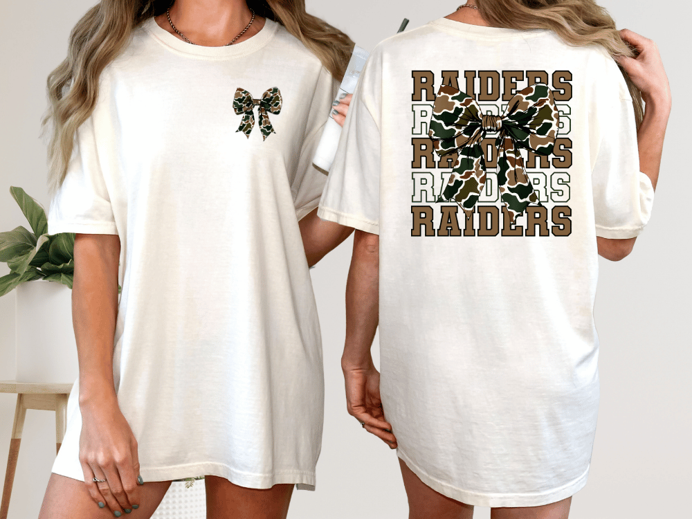 A woman wearing a white t-shirt with a camouflage design and the word "RAIDERS" printed on the back.