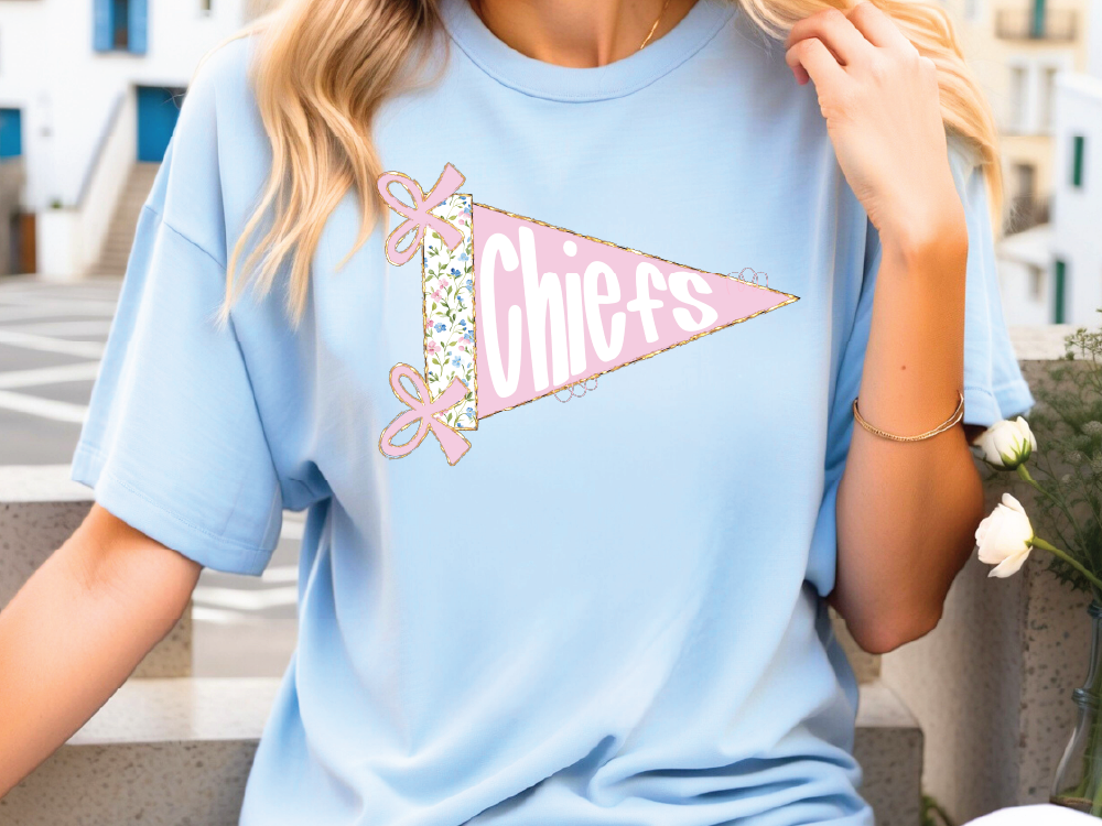 A woman wearing a light blue t-shirt with a pink and white design on it.
