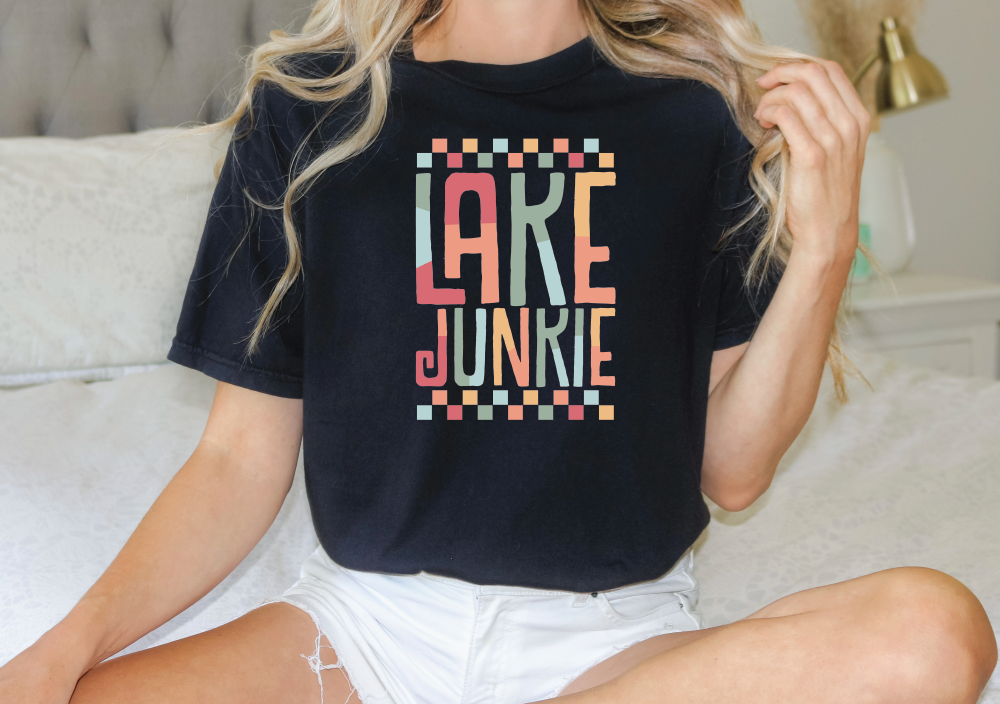 a woman sitting on a bed wearing a lake junkie shirt