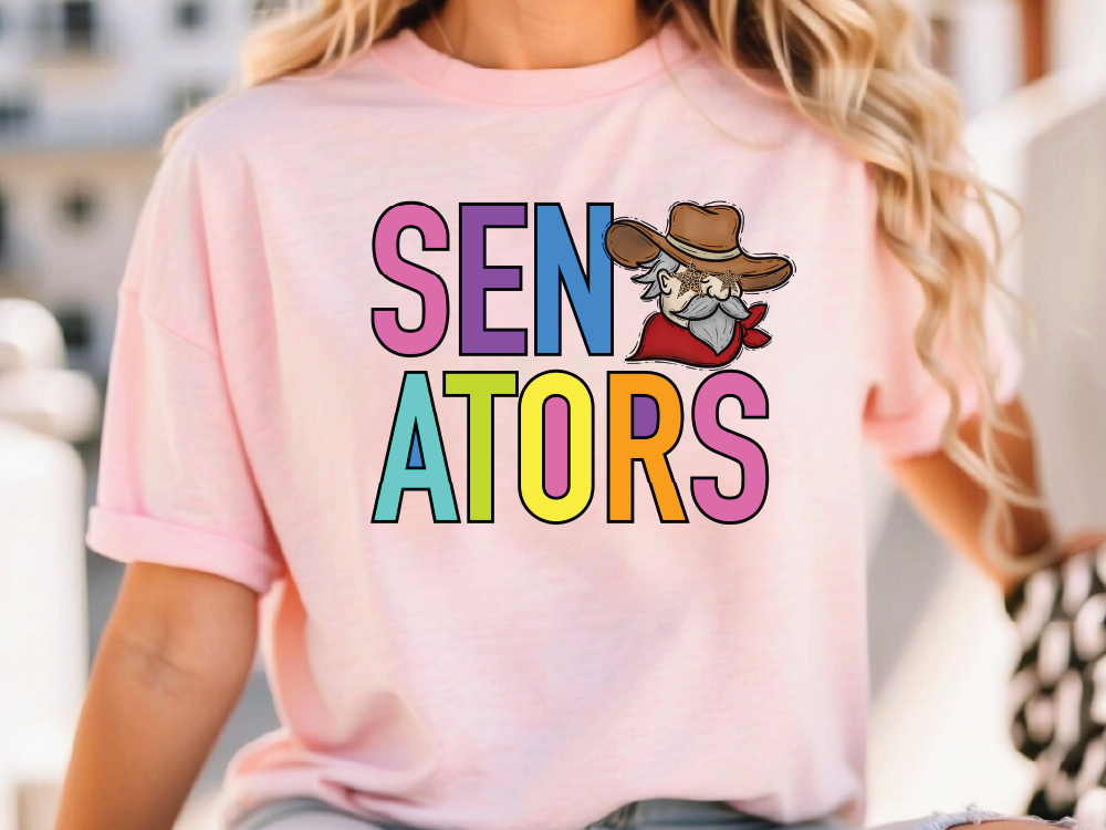 A woman wearing a pink t-shirt with the text "SENATORS" and a cartoon cowboy graphic printed on it.