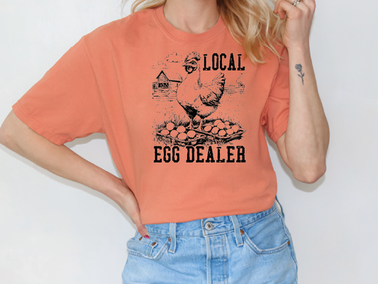 a woman wearing an orange shirt that says local egg dealer