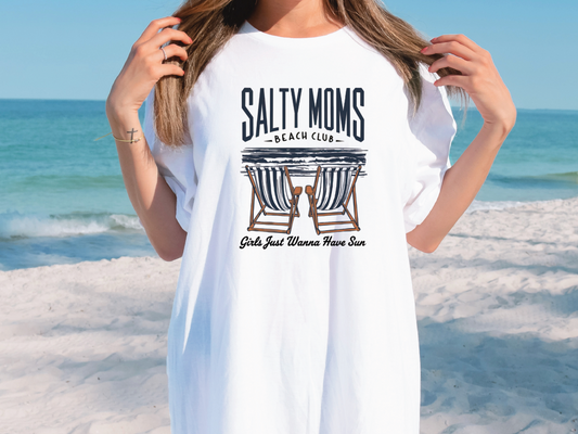 a woman standing on a beach wearing a white shirt