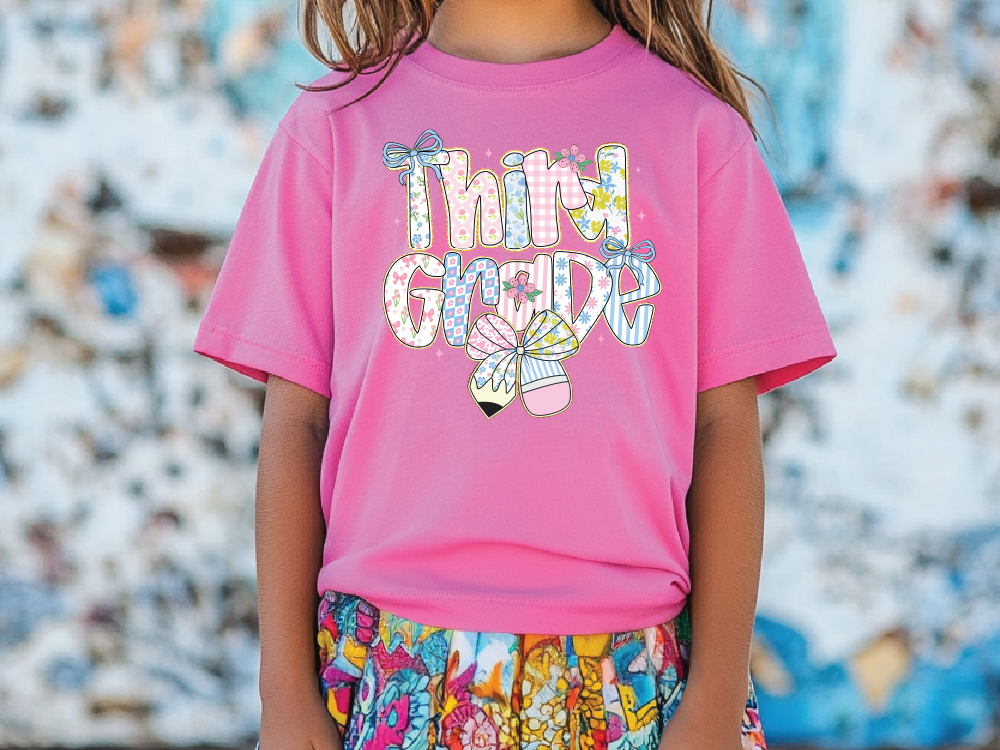 a little girl wearing a pink shirt and colorful shorts