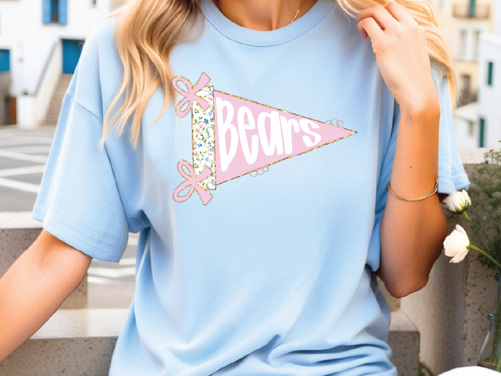 A woman wearing a light blue t-shirt with a pink and white design that says "Bears" on it.